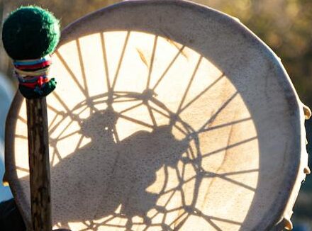 musician playing hand drum outdoors at sunset