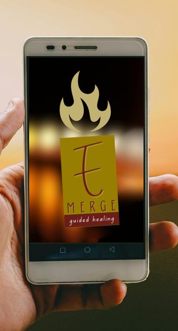 Hand holding smartphone with Emerge GuidedHealing logo on screen, glowing in golden light, symbolizing access to spiritual and healing content online.