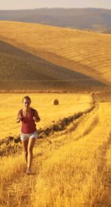 Woman with a backpack walking through a goden hay. field, symbolizing a Reiki healing journey